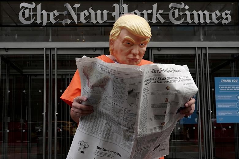 Mike Hisey dressed as President Trump in a prison jumpsuit reads the New York Times in front of the New York Times office in Manhattan.  REUTERS/Carlo Allegri  